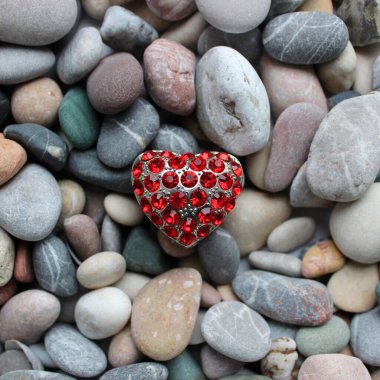 Pürüzsüz renkli taşların üzerinde kırmızı mücevherlerle süslenmiş gümüş bir kolye.