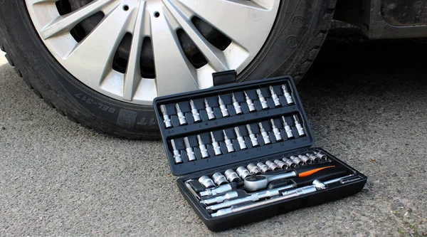 Car Tools In Plastic Case With Open Lid Near Front Wheel Of Car