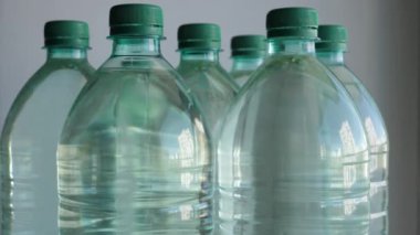Beyaz arka planda sırayla suyla dolu aynı plastik şişelerin 4K videosu