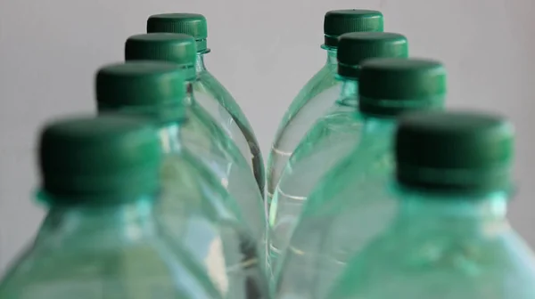 白に隔離された最後のボトルに焦点を当てたプラスチック製の水ボトルの2列 — ストック写真