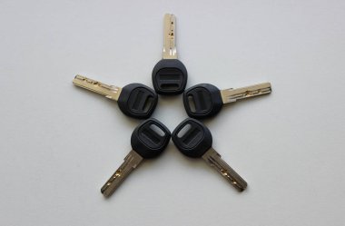 Plastik başlıklı anahtarların, beyaz yüzeye serilmiş çiçek formunda ön görünümü