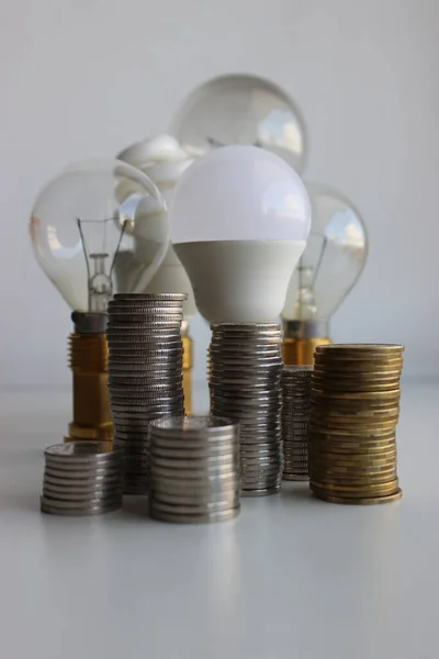 Stock image Columns of coins in front of different lamps as an illustration electricity cost 