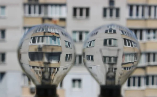 两个脱色的灯丝灯泡作为放大镜 可以看到公寓楼的正面 — 图库照片
