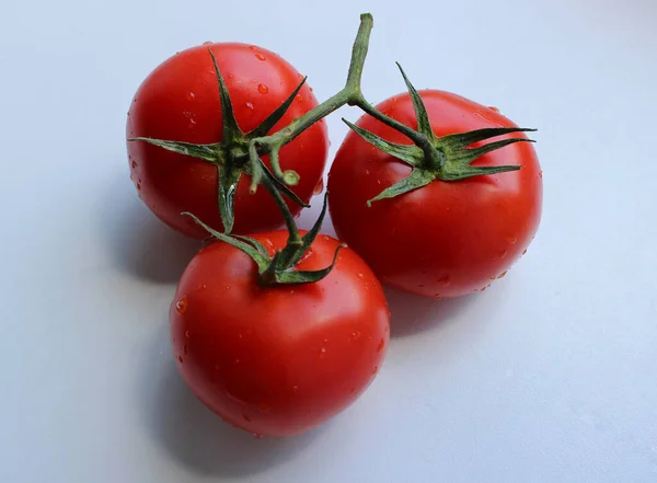 白色塑料切割板上的一个分枝上的三个完整的西红柿 — 图库照片