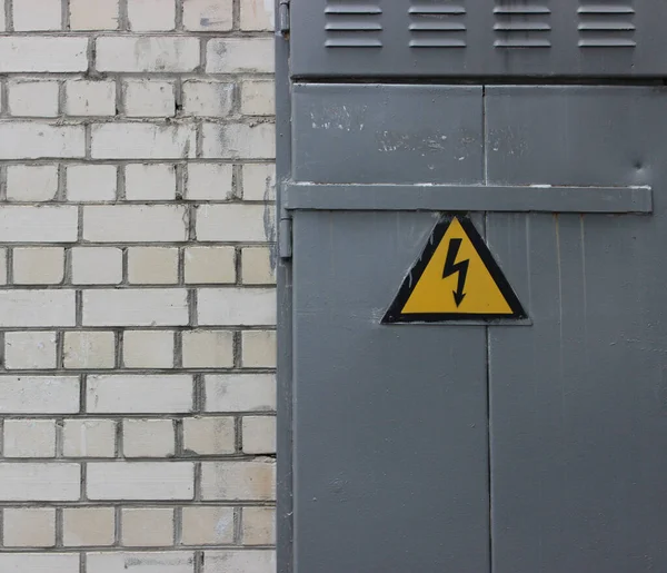 High Voltage Sign On A Steel Door On A White Brick Wall Texture Background