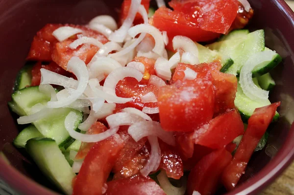 stock image Cutted Fresh Cucumbers, Tomatoes And White Onion Sprinkled With Coarse Salt In A Salad Plate Closeup View