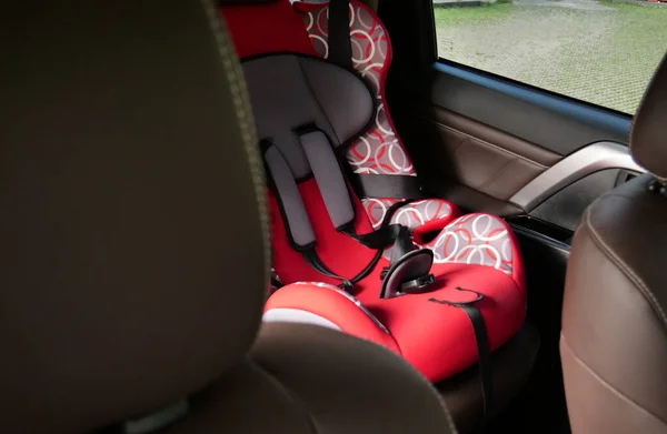 Child safety seat in the rear seat of a car fixed with seat belts