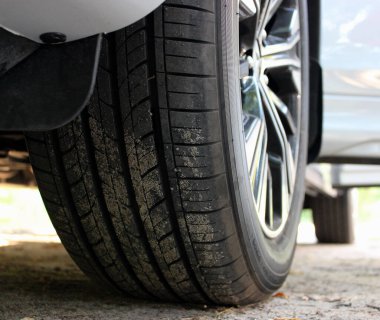 Kumsala yakın manzaralı, kapısı açık beyaz bir arabanın ön tekerleği. 