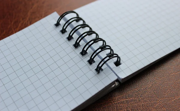 Opened spiral notebook on leather table detailed stock photo