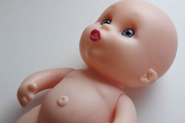 Beyaz yüzeyde yatan üzgün gözlü oyuncak bebek. Ayrıntılı stok fotoğrafı. 