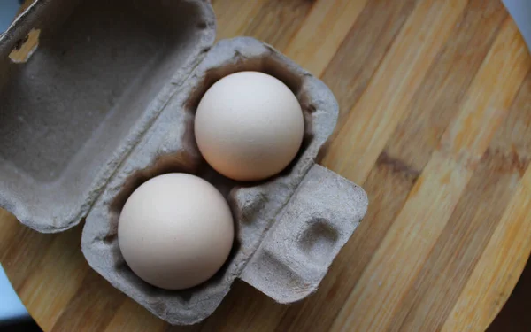 Domestic chicken eggs in a small cardboard box for two eggs. Country eggs concept stock photo