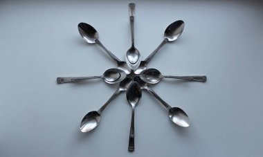 Beyaz yüzeyde çeşitli boyutlarda kaşıklarla yapılan çiçek desenleri / Değişken boyutta kaşıklarla yapılan yıldız desenleri beyaz yüzeyde izole edilmiş  