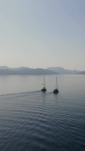 两艘帆船在美丽的落日下从海峡驶向平静大海的垂直录像 — 图库视频影像