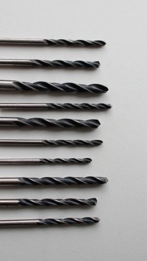 Beyaz yüzeyde çeşitli siyah matkaplar var. Dikey arkaplan için Stok Fotoğrafı