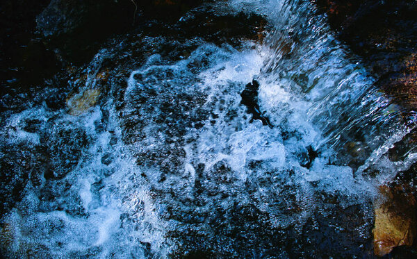 Spring water bubbles in a small waterfall of a mountain stream