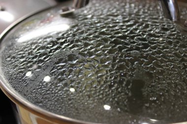 Drops of hot condensation on the glass lid of a frying pan   clipart