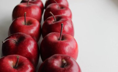 Resmin beyaz yüzeyinde organik kırmızı elma meyveleri olan sıraların açılı görüntüsü. Elma Meyveleri Beyaz Stok Fotoğrafında İzole Edildi