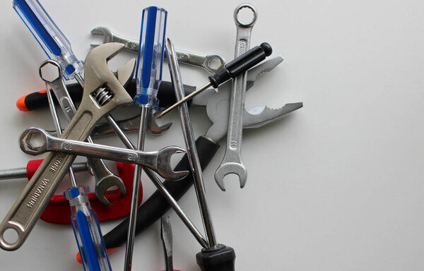Куча цветных плоскогубцев, прутков, ключей, отверток, зажимов и шестигранных ключей, изолированных на белом с одной стороны изображения