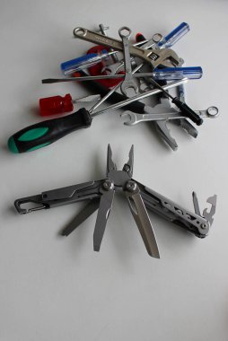Folding utility knife with blades spread out against a pile of unnecessary tools vertical stock photo