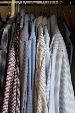 Üst gardırop kompartımanında askılı klasik tişörtler var. Giysi depolama illüstrasyonu için dikey stok fotoğraf