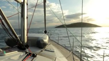 Bir yatın sallanan güvertesinde, deniz adası yakınlarındaki güçlü bir rüzgarda sallanan bir sandalla. Full HD 'de yatta deniz yolculuğu videosu.