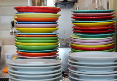 Mutfakta yıkandıktan sonra beyaz tabaklar ve farklı renklerde tabaklar.