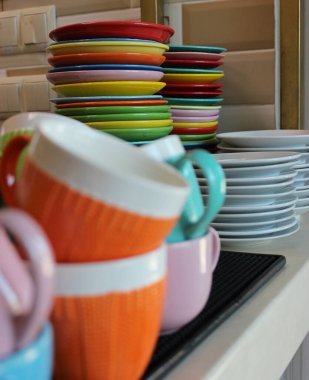 Tatil partisinden sonra dağınık renkli bardakların arkasında renkli tabak yığını olan mutfak masası. 