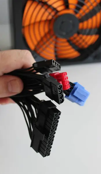 stock image Hand of a computer technician holding a bundle of cables with different connectors for connecting a power supply to computer system unit