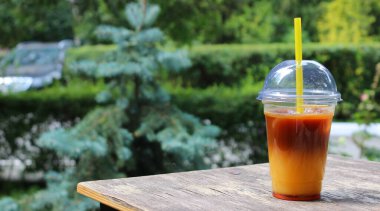 Açık bir kafede bir fincan buzlu portakallı kahve ile küçük bir masa.