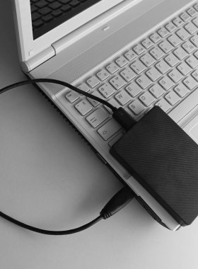 Harici sabit disk beyaz masadaki beyaz dizüstüne bağlandı