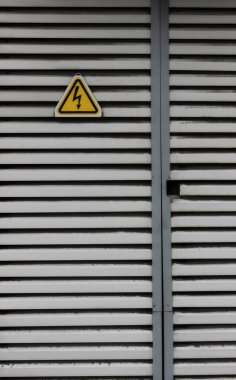 Yüksek voltajlı transformatör kapısı ve yüksek voltajlı risk işareti. Güç ve Enerji Arkaplanları için Dikey Resim