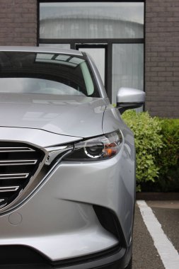 Araba dükkanının önündeki modern bir arabanın ön tarafında. Satılık araba stok fotoğrafı. Mağazanın yanındaki modern arabanın ızgara ve farları. 