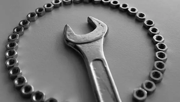 Stock image Steel spanner inside of perfect ring made with fastener nuts grayscale stock photo. Mechanical workshop illustrative background