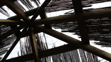 Geometric structure of supporting beams inside a wooden cabin with a reed roof under construction clipart