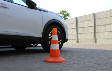 Açık hava otoparkındaki arabanın yanında park konisi. Yol Güvenliği Konileri Stok Resmi 