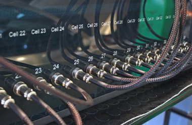 Özel atölyede elektrikli araçların batarya hücrelerini test etmek için cihaza yerleştirilmiş örgülü kablolar 