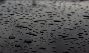 Karanlık, parlak bir yüzeyde şiddetli soğuk yağmur damlaları. Karanlık havada sonbahar yağmur damlaları