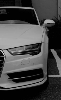 Park yerinde beyaz çizgilerle işaretlenmiş beyaz modern premium arabanın farları. Dikey gri tonlu araba duvar kâğıdı 