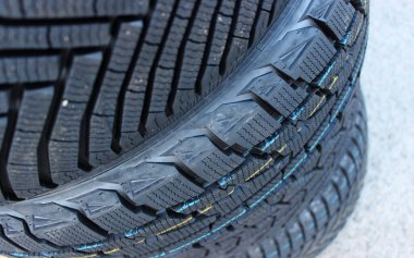 New Winter Tires Stacked On Asphalt Closeup Stock Image. Studless Tires Details clipart