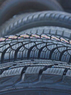 A row of car tires leaning against each other and standing on edge selective focus. Tire workshop vertical image  clipart