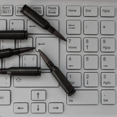 Balistik Laboratuvarı ve Araştırma. Beyaz bir dizüstü bilgisayarın klavyesindeki Giriş Anahtarı 'nın Etrafındaki Mermi Kartuş. Suç Araştırma Tek Krom Stok Fotoğrafı