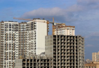 İnşaat halindeki yüksek katlı bir binanın beton iskeleti zaten inşa edilmiş konut binalarını çakıştırıyor.