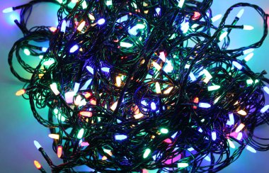 Küçük renkli ampullerle parıldayan bir Noel çelenginin birbirine dolanmış telleri. Parlayan çelenk beyaza izole edilmiş Tatil Arkaplanı  