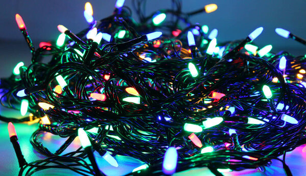 Twisted garland wires with LED bulbs shines into darkness isolated on white panoramic image. Holiday illumination and decoration stock photo 