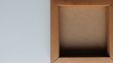 Beyaz yüzeyin tam olarak yarısı düz bir karton kutuyla kaplı. Arkaplan için Ambalaj Ögeleri Stok Fotoğrafı