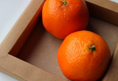 Pair of Ripe Fresh Tangerines in a Craft Tray Angle View Closeup Image. Paper Tray for Fruits Detailed Stock Photo  clipart