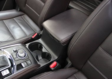 Koltukların arasındaki koltukların yanında iki adet yuvarlak bardak tutacağı ve pahalı deri süslemeler. Premium bir arabayla uzun bir yolculuk için konfor ve kolaylık 