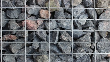 Açık hava dekorasyonları için Taş Duvar 'daki Fored Granite Parça Arkaplanı. Bir Metal Kafes Çitin İçinde Moloz Taşları Tutar