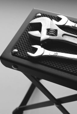 Değişik boyutlarda siyah beyaz fotoğraf ve masa desteği altlığının kauçuk yüzeyinde ayarlanabilir İngiliz anahtarı. Çalışma yerinde düzen gri ölçekli hisse senedi imajı