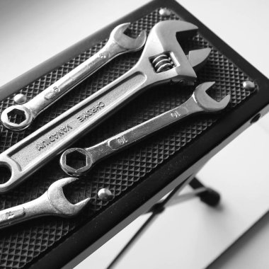 Kare gri ölçekli plastik masa rafı ve mekanik aletler. Çelik anahtarlar ve ayarlanabilir anahtarlar küçük araç standında izole edildi 